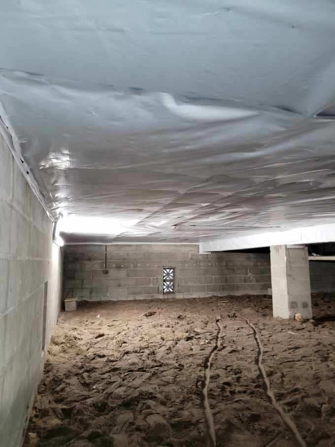 Bright white plastic vapor barrier installed across the ceiling joists of a dirt floor crawlspace Bright white plastic vapor barrier installed across the ceiling joists of a dirt floor crawlspace