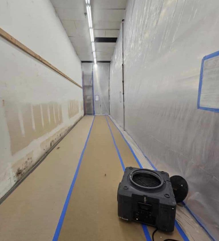 Long hallway sealed off with plastic containment barriers and blue painters tape with an air scrubber operating on the floor Long hallway sealed off with plastic containment barriers and blue painters tape with an air scrubber operating on the floor