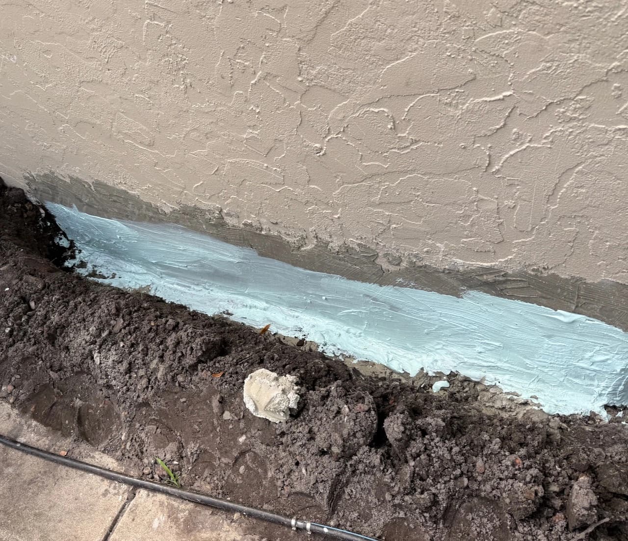 Fresh waterproofing seal applied along the exterior base of a Florida home after water intrusion Fresh waterproofing seal applied along the exterior base of a Florida home after water intrusion
