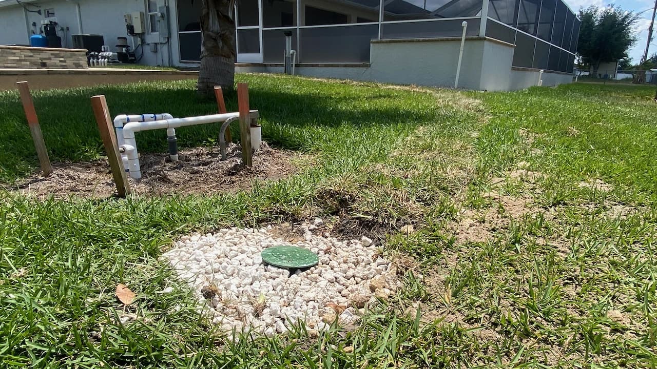 Completed gravel drainage bed and cleanout beside a Florida home foundation Completed gravel drainage bed and cleanout beside a Florida home foundation