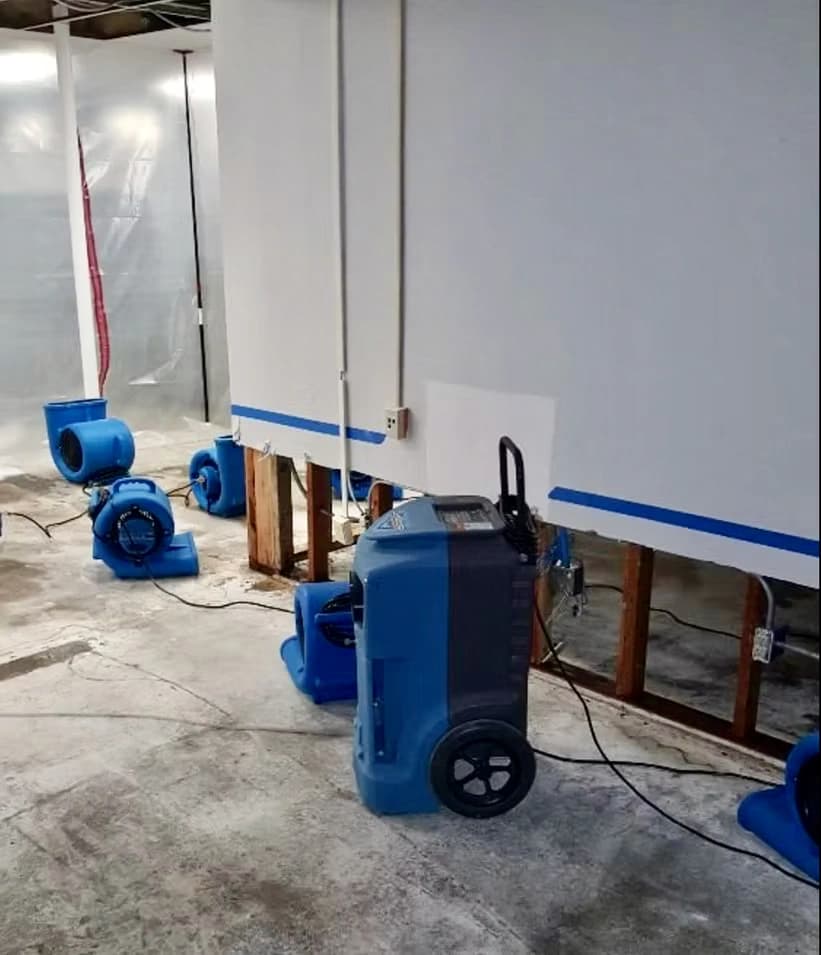 Commercial dehumidifier and air movers drying a room after the lower drywall was cut away Commercial dehumidifier and air movers drying a room after the lower drywall was cut away